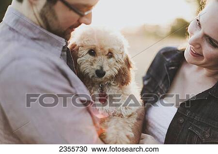 A couple holding their pet dog; Crescent Beach, British Columbia, Canada View Large Photo Image Stock Image - A couple holding their pet dog; Crescent Beach, British Columbia, Canada. Fotosearch