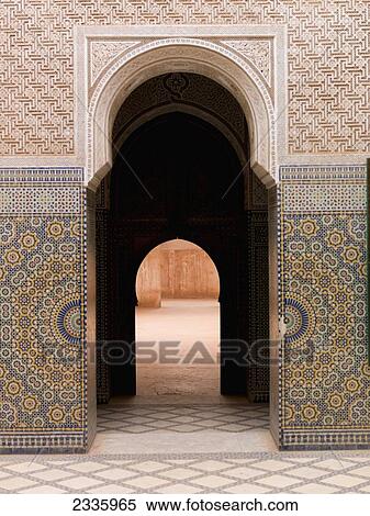 Stock Photography - A doorway in a keyhole shape with a colourful tile design on the wall. Fotosearch