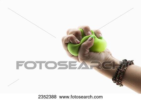Stock Photo - A female hand squeezing a stress ball against a white background; California, United States of America. Fotosearch
