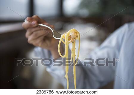 A hand holding a fork full of pasta View Large Photo Image Stock Photograph - A hand holding a fork full of pasta. Fotosearch