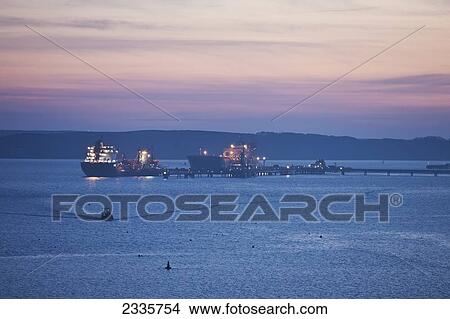 A large boat and pier illuminated at sunset in a river View Large Photo Image Picture - A large boat and pier illuminated at sunset in a river. Fotosearch