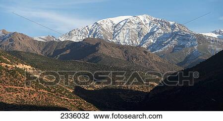 Stock Image - A large rugged mountain with snow against a blue sky. Fotosearch
