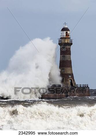 Stock Photography - A large wave crashing into a lighthouse; Sunderland, Tyne and Wear, England. Fotosearch