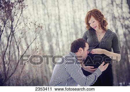Stock Image - A man kissing his pregnant wife's belly; Edmonton, Alberta, Canada. Fotosearch