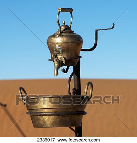 A metal teapot with a tap and bucket below with a sandy landscape and blue sky View Large Photo Image Stock Photo - A metal teapot with a tap and bucket below with a sandy landscape and blue sky. Fotosearch