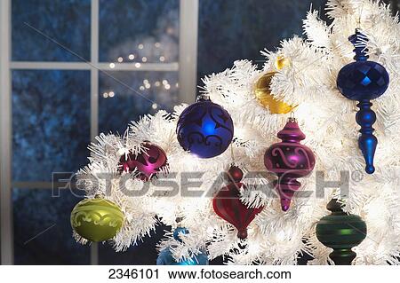A section of a white Christmas tree with colorful ornaments hanging off of it in front of a moonlit window; California, United States of America View Large Photo Image Stock Image - A section of a white Christmas tree with colorful ornaments hanging off of it in front of a moonlit window; California, United States of America. Fotosearch