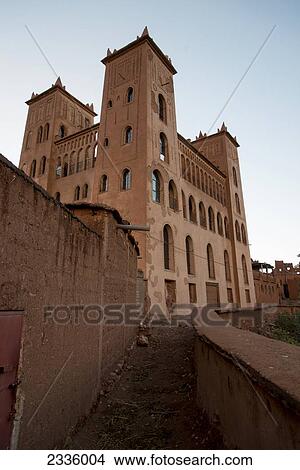 Picture - A walking path along a wall and a building against a blue sky. Fotosearch