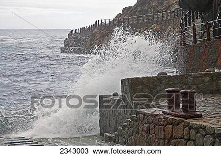 A wave crashing into a stone wall on the coast; Tenerife, Canary Islands, Spain View Large Photo Image Stock Image - A wave crashing into a stone wall on the coast; Tenerife, Canary Islands, Spain. Fotosearch