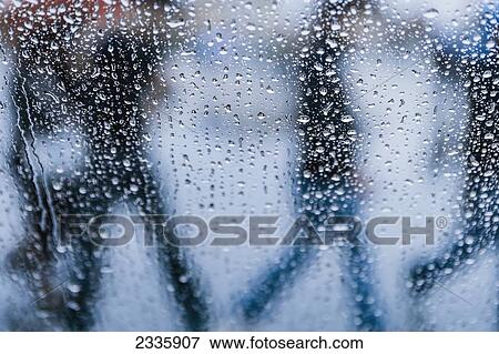 A window covered with rain drops and silhouettes of people walking by on the outside View Large Photo Image Stock Photo - A window covered with rain drops and silhouettes of people walking by on the outside. Fotosearch