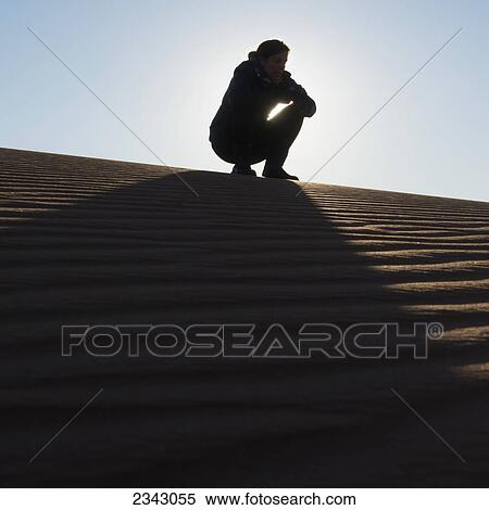 A woman crouching on the top of a sand dune; Souss-Massa-Draa, Morocco View Large Photo Image Stock Photography - A woman crouching on the top of a sand dune; Souss-Massa-Draa, Morocco. Fotosearch