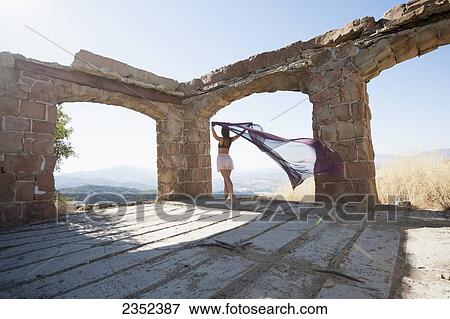 A woman holding a piece of sheer fabric behind her as it flows in the wind within some ruined arches; Santa Barbara, California, United States of America View Large Photo Image Stock Photo - A woman holding a piece of sheer fabric behind her as it flows in the wind within some ruined arches; Santa Barbara, California, United States of America. Fotosearch