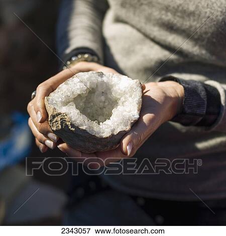 Stock Photo - A woman holds sliced fruit to reveal the flesh; Morocco. Fotosearch