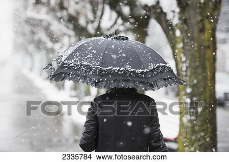 Picture - A woman walking in a snowfall with an umbrella. Fotosearch
