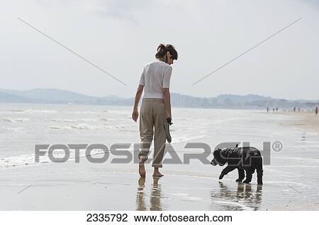 A woman walking with her dog on the beach View Large Photo Image Stock Image - A woman walking with her dog on the beach. Fotosearch