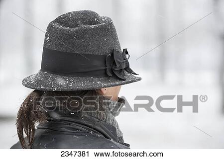 Stock Image - A woman wearing a hat in a snowfall; Locarno, Ticino, Switzerland. Fotosearch
