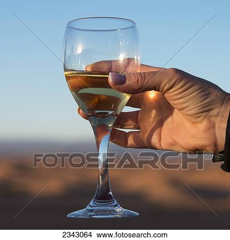 Picture - A woman's hand holding a glass of white wine; Souss-Massa-Draa, Morocco. Fotosearch