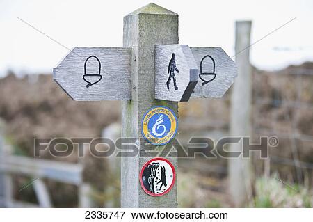 Stock Photo - A wooden post and directional signs for walking paths; Wales. Fotosearch