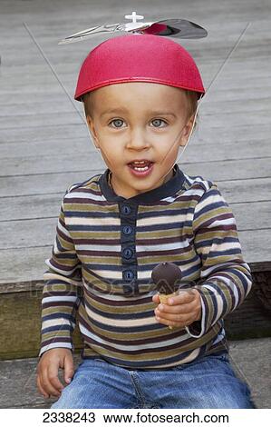 A young boy wearing a helicopter hat and holding a small chocolate treat; Pacifica, California, United States of America View Large Photo Image Stock Image - A young boy wearing a helicopter hat and holding a small chocolate treat; Pacifica, California, United States of America. Fotosearch