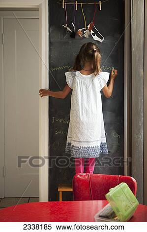 Stock Photography - A young girl stands drawing on a chalkboard wall; San Francisco, California, United States of America. Fotosearch