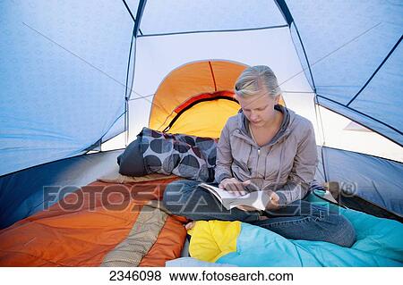 Stock Photo - A young woman reading a book inside a tent; California, United States of America. Fotosearch