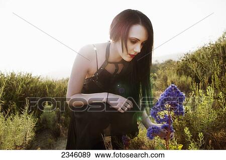 A young woman touching a purple flower with the sun behind her; California, United States of America View Large Photo Image Stock Photo - A young woman touching a purple flower with the sun behind her; California, United States of America. Fotosearch