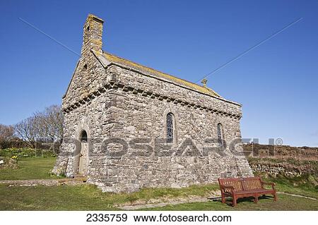 Stock Photo - An old stone church with a bench and blue sky. Fotosearch
