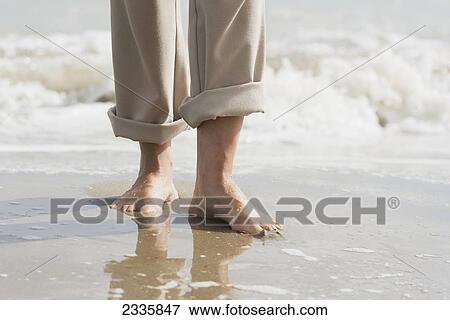 Stock Photo - Barefoot in the wet sand with waves coming in the tide. Fotosearch