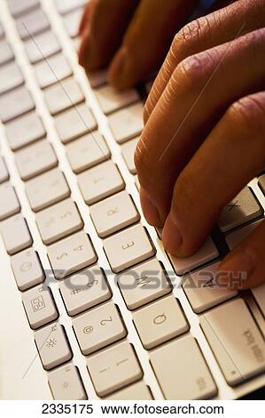 Stock Photography - Close up of computer keyboard with fingers typing; Calgary, Alberta, Canada. Fotosearch