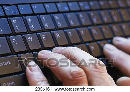Stock Image - Close up of fingers typing on a keyboard; Calgary, Alberta, Canada. Fotosearch