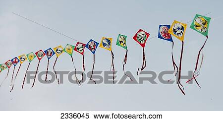 Stock Photography - Colourful kites with faces on them in a row against a blue sky. Fotosearch