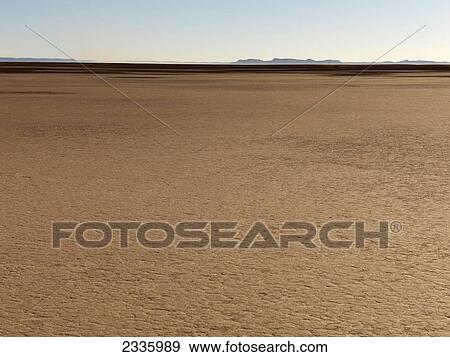 Stock Photo - Flat arid and barren landscape with some mountains in the distance. Fotosearch