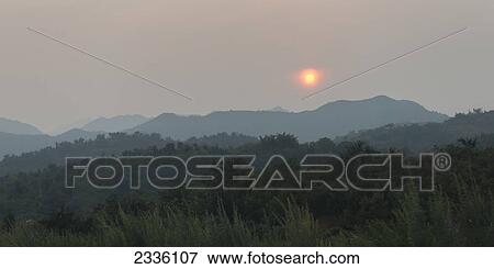 Stock Photo - Glowing sun over the mountainous landscape and the Great Wall; Beijing, China. Fotosearch