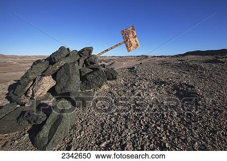 Stock Image - Graphite rocks at Dias Point and a rusted old sign; Luderitiz, Namibia. Fotosearch