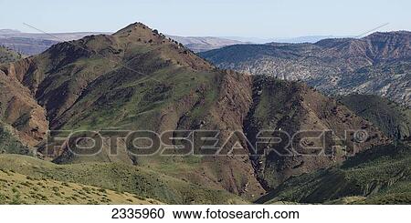 Stock Image - Landscape of mountains and valleys under a blue sky. Fotosearch