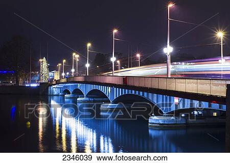 Stock Photo - Lights illuminate a bridge over Lake Zurich at night; Zurich, Switzerland. Fotosearch