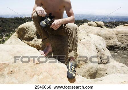 Man putting on his rock climbing shoes at the top of Lizard's Mouth; Santa Barbara, California, United States of America View Large Photo Image Stock Photo - Man putting on his rock climbing shoes at the top of Lizard's Mouth; Santa Barbara, California, United States of America. Fotosearch