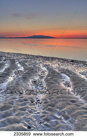 Ripples and patterns in the sand at the water's edge with a pink sunset on the horizon View Large Photo Image Stock Photo - Ripples and patterns in the sand at the water's edge with a pink sunset on the horizon. Fotosearch