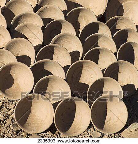 Stock Image - Rows of clay bowls on display on the ground. Fotosearch