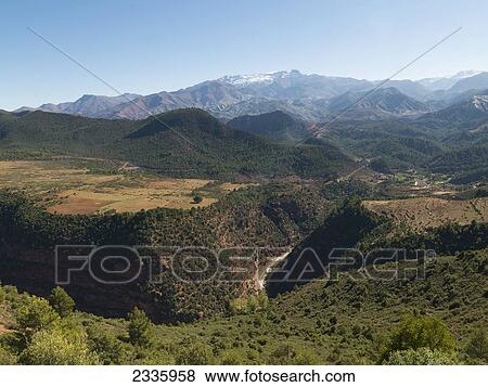 Rugged landscape of hills and mountains under a blue sky View Large Photo Image Stock Photo - Rugged landscape of hills and mountains under a blue sky. Fotosearch