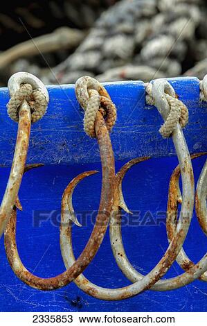 Stock Image - Rusted hooks tied onto a blue edge. Fotosearch