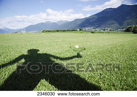 Shadow of a person holding a racquet being cast onto a ball sitting on the grass; Locarno, Ticino, Switzerland View Large Photo Image Stock Image - Shadow of a person holding a racquet being cast onto a ball sitting on the grass; Locarno, Ticino, Switzerland. Fotosearch
