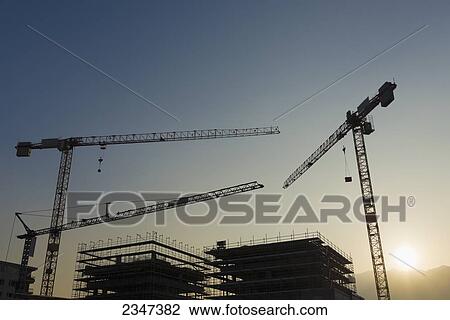 Silhouette of cranes and frames of buildings under construction at sunset; Locarno, Ticino, Switzerland View Large Photo Image Stock Image - Silhouette of cranes and frames of buildings under construction at sunset; Locarno, Ticino, Switzerland. Fotosearch