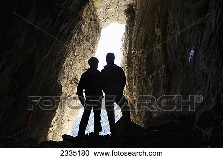 Silhouette of two male hikers in cave with entrance glowing in the background; Bragg Creek, Alberta, Canada View Large Photo Image Stock Image - Silhouette of two male hikers in cave with entrance glowing in the background; Bragg Creek, Alberta, Canada. Fotosearch