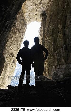 Silhouette of two male hikers in cave with entrance glowing in the background; Bragg Creek, Alberta, Canada View Large Photo Image Stock Photo - Silhouette of two male hikers in cave with entrance glowing in the background; Bragg Creek, Alberta, Canada. Fotosearch