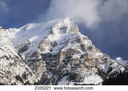 Stock Image - Snow covered mountain with blue sky and cloud; Kananaskis Country, Alberta, Canada. Fotosearch