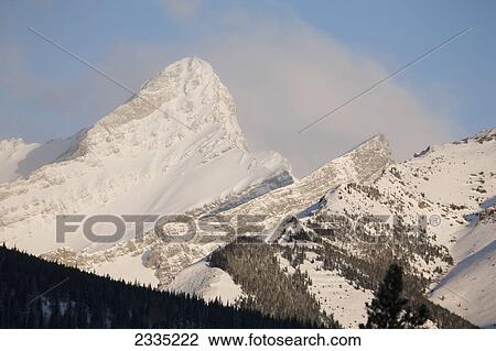 Stock Image - Snow covered mountain with blue sky and cloud; Kananaskis Country, Alberta, Canada. Fotosearch