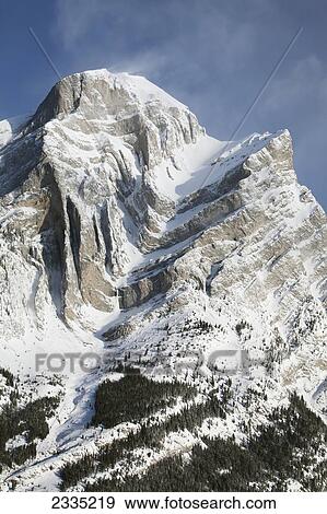Snow covered mountain with blue sky and cloud; Kananaskis Country, Alberta, Canada View Large Photo Image Stock Photo - Snow covered mountain with blue sky and cloud; Kananaskis Country, Alberta, Canada. Fotosearch