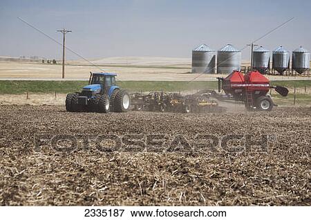 Stock Photo - Tractor with air seeder planting crop in field with blue sky; Alberta, Canada. Fotosearch