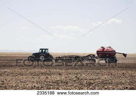 Tractor with air seeder planting crop in field with blue sky and clouds; Alberta, Canada View Large Photo Image Stock Photo - Tractor with air seeder planting crop in field with blue sky and clouds; Alberta, Canada. Fotosearch