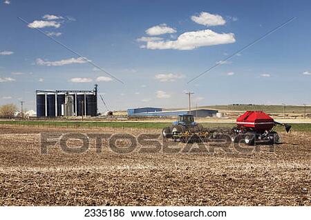 Tractor with air seeder planting crop in field with blue sky and clouds; Alberta, Canada View Large Photo Image Stock Photograph - Tractor with air seeder planting crop in field with blue sky and clouds; Alberta, Canada. Fotosearch